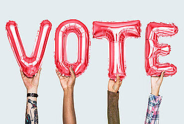 Hände halten Ballons mit Schriftzug VOTE