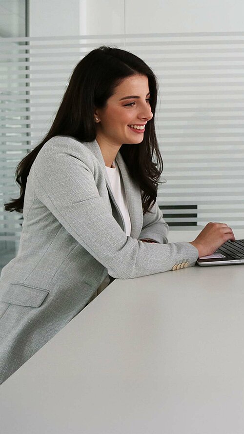 Zwei Personen im modernen Büro tauschen sich über berufliche Themen aus und arbeiten gemeinsam am Laptop