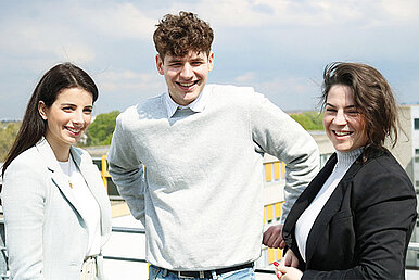 Drei Mitarbeiter stehen zusammen draußen auf der Dachterasse