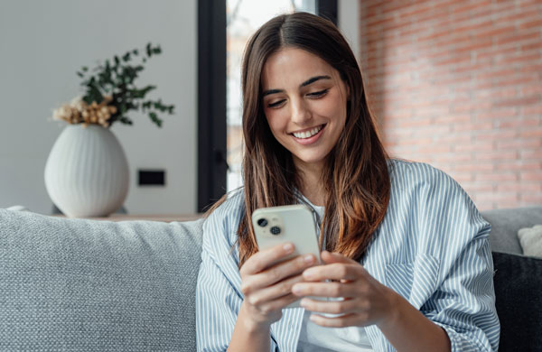 Junge Frau blickt auf ihr Smartphone in der Hand